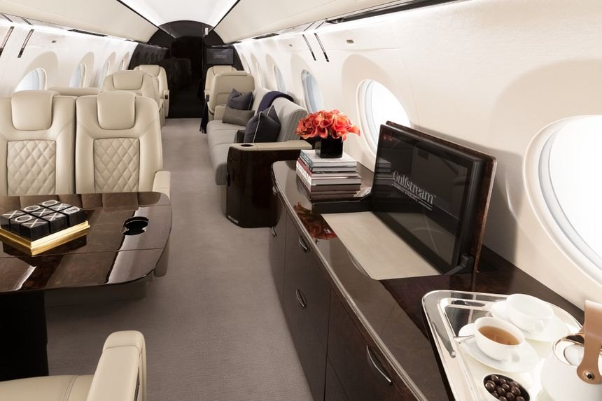 Heavy jet cabin with cream leather seats, a sofa and a dining table
