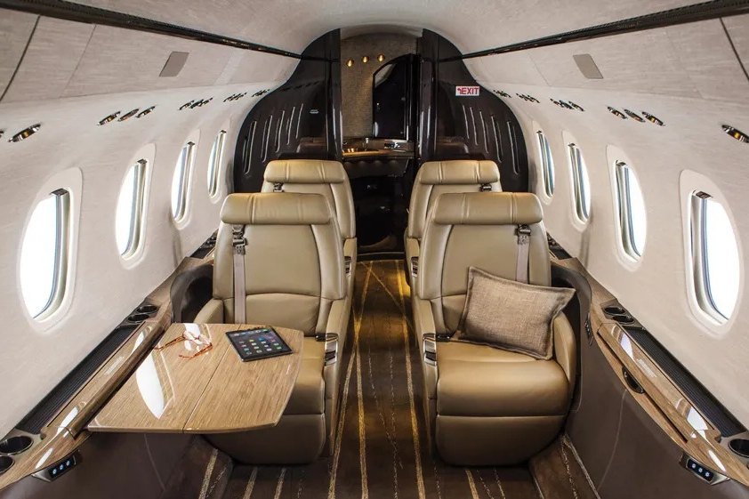 Mid jet cabin with beige leather seats and wood trim