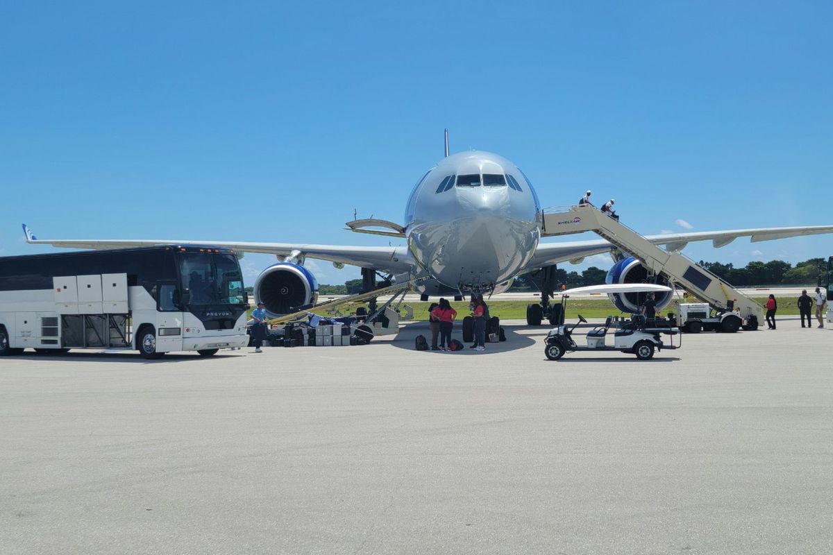 Group charter airliner on the ramp with motor coaches alongside